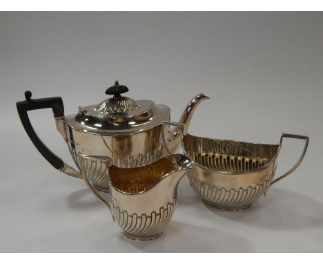 An Edwardian silver three piece oval tea set, with part fluted decoration, comprising teapot, sugar basin and cream jug, Shef