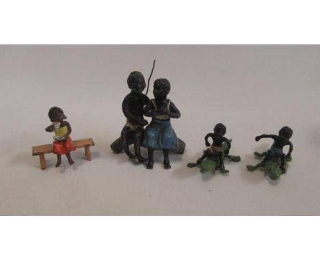 Four cold painted metal blackamoor figures comprising couple seated on trunk, two boys on crocodiles and another on a bench, 