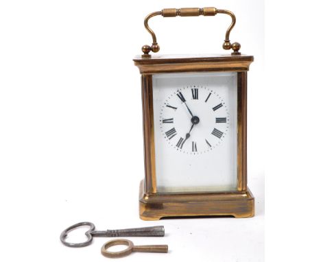 An early 20th-century carriage clock, with a brass case and handle, glass beveled sides, and a see-through oval window to the
