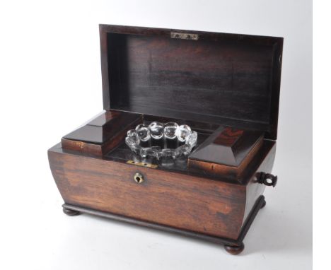 A 19th-century mahogany sarcophagus tea caddy, featuring twin compartments with brass hinged, beveled lids, a glass mix bowl,