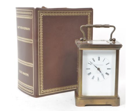 Matthew Norman - A 20th-century brass carriage clock, made in Switzerland. With beveled glass paneling, a brass handle, an en
