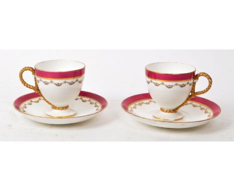 Two 19th-century porcelain teacups and saucers, featuring rope twist handles to the teacups, a pink / purple bordered rim, an