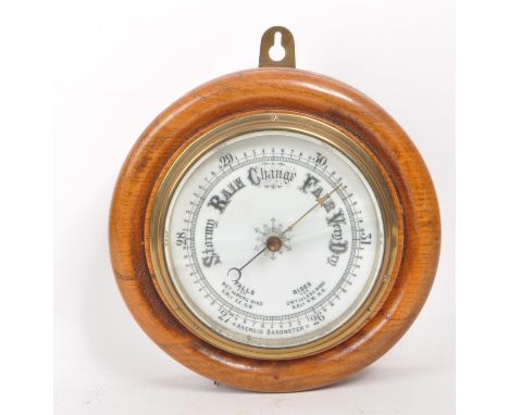 A late 19th century Victorian aneroid barometer, mounted on an oak plinth base, with brass mounts and a porcelain face with b