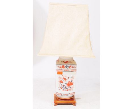 An early 20th century Chinese ceramic imari style lamp, raised on a wooden structure with four short legs. Featuring red and 