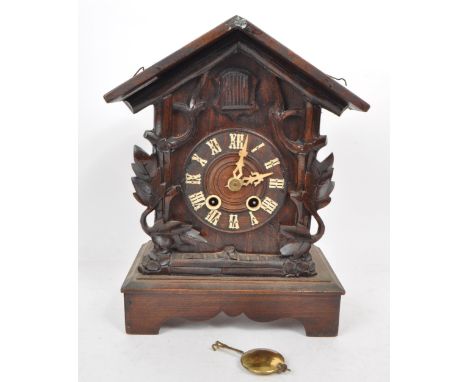 An early 20th century carved wooden mantel cuckoo clock, in the style of black forest. Featuring an enamel Roman numeral chap