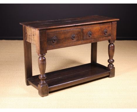 A 17th Century Oak Table of bold proportions. The top having a plate groove to the back above two frieze drawers with iron lo