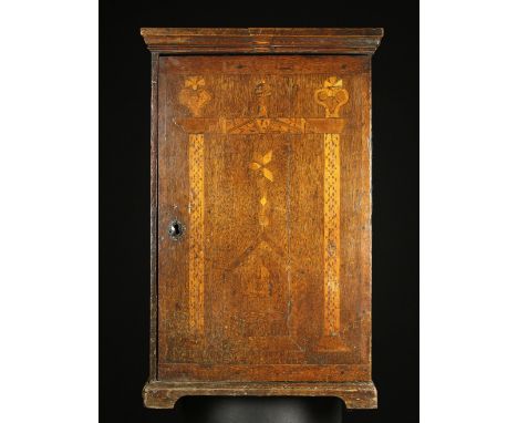 An 18th Century Marquetry Spice Cabinet. The door decorated with provincial folksy inlay incorporating peg-work, the initials