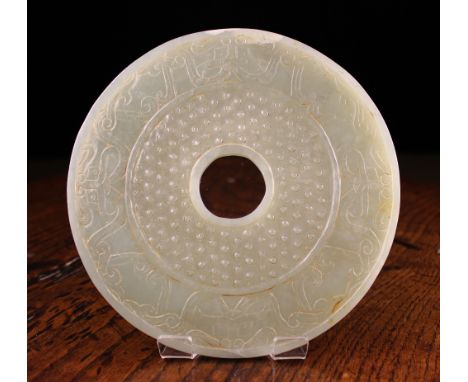 A Han Period Jade Bi Ornament: The pierced circular disc carved on both sides with an outer band of entwined scrollwork incor