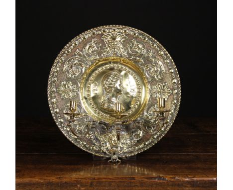 A 19th Century Decorative Embossed Brass Wall Sconce. The three scrolling candle branches emanating from a cast face-mask mou