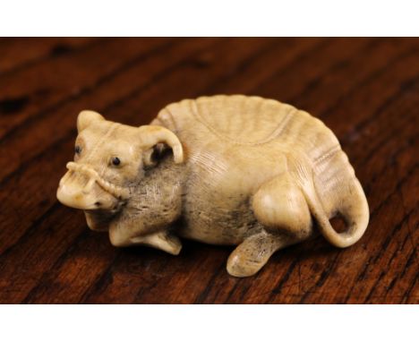 A 19th Century Stag Horn Netsuke signed Tomo Masa, carved in the form of a recumbent ox, 1 inch (2.6 cm) high, 2¼ ins x 1⅜ in