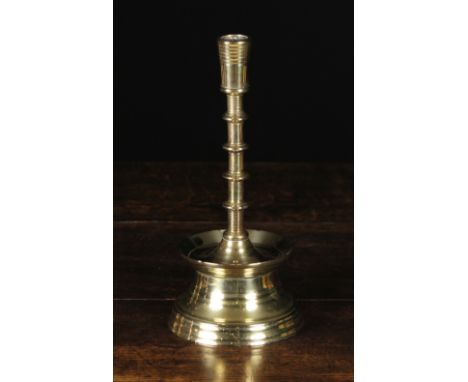 A Heavy 16th Century Style Brass Candlestick having a reeded bucket socket (unpierced) above a tall cylindrical stem with fiv