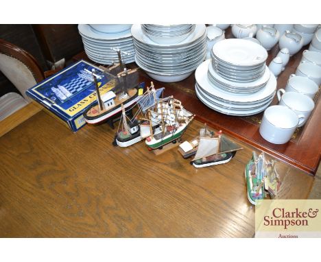 A glass chess set and various wooden and other model boats