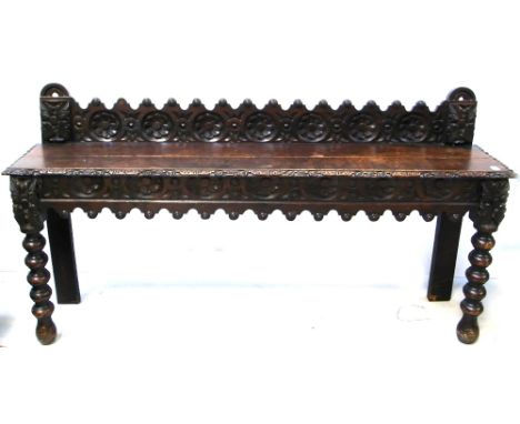 An early 20th century heavily carved oak hall bench of small proportions on turned legs, width 115cm.
