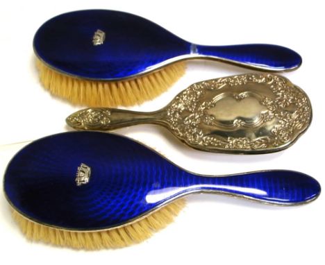 A pair of George VI hallmarked silver and enamel backed brushes, Birmingham 1947, and a further white metal example (3).
