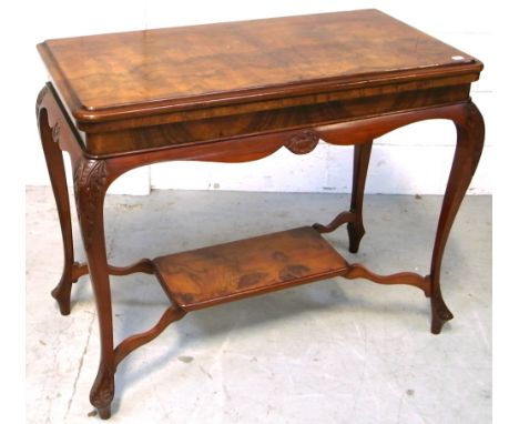 A walnut fold over card table with foliate and shell carved decoration with lower shelf, width 93cm.