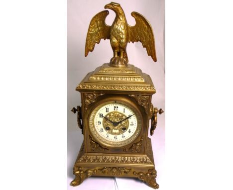 A late 19th early 20th century French gilded clock with eagle decoration to the top on a stacked plinth, the enamel and gilde