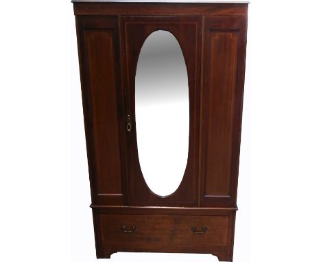 A late 19th early 20th century mahogany and inlaid wardrobe, central panel with bevelled oval mirror to a long drawer and bra