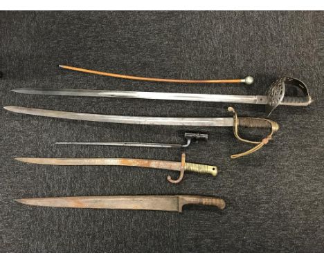 A collection of various swords, bayonets and a swagger stick