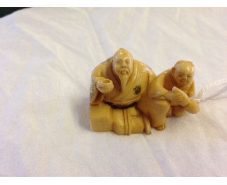 A signed netsuke of 2 figures drinking.