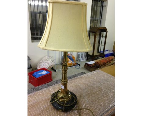 A brass table lamp made from a vintage fire hose nozzle on a carved wooden base.