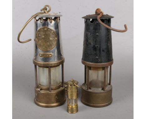 Two vintage miners lamps along with a miniature example.  