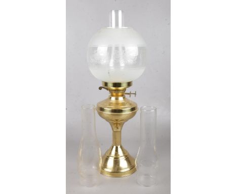 A brass based oil lamp with etched glass shade and spare chimneys.  