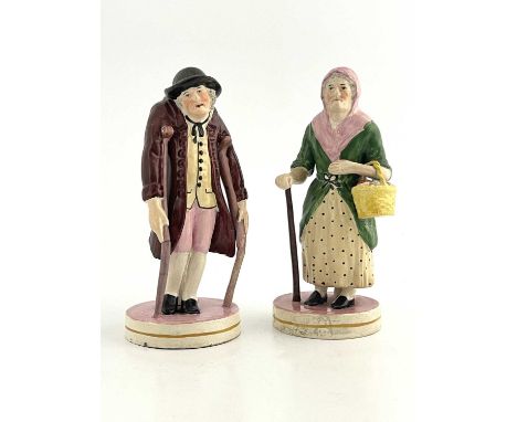 A pair of Staffordshire pearlware figures of Old Age, each on circular bases, modelled as a man on crutches and a woman with 