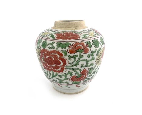 A Chinese polychrome ginger jar, probably Ming, painted with iron red peonies within a green foliate scroll ground, 16cm high