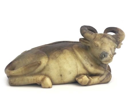 A Chinese jade style carved figure of an ox, modelled reclining, russet horns and veins, 27cm long