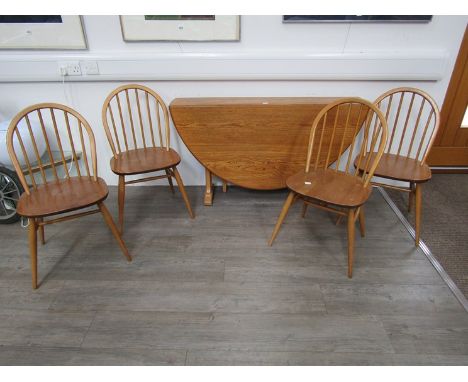 An Ercol light elm folding dining table together with four stick back dining chairs. Table 128cm long x 138cm fully extended.