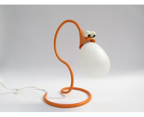An orange table lamp with comical snake face shade 