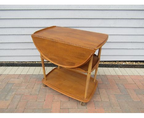 An Ercol light elm three tiered trolley with drop down sides 