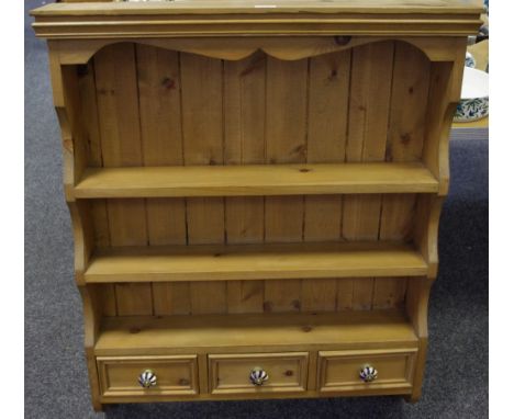 A country pine wall mounted shelving unit, shaped uprights, three shelves over three short drawers, lobed ceramic handles. 10