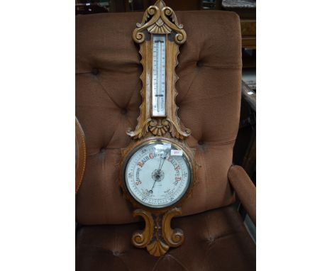 A late 19th or early 20th Century oak framed banjo thermometer in ornately carved case