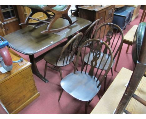 An Ercol Dark Elm Dining Table, rectangular top, rounded ends, with stretchered trestle ends and four spindle back dining cha