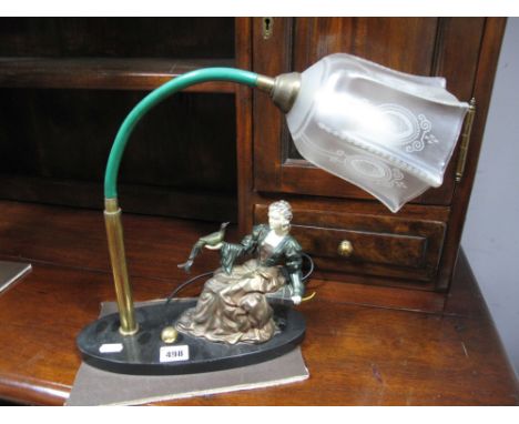 A Circa 1930's Desk Lamp, arched brass cased lamp with etched frosted shade beside a seated bronzed lady in a gown holding a 