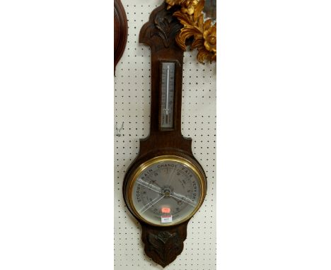 A mid 20th century carved oak aneroid two dial wheel barometer