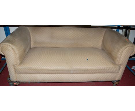 An Edwardian and upholstered three seater sofa raised on bun supports