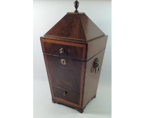 A George III mahogany sarcophagus form decanter box with urn finial and lion mask handles, drawer to base, 58cm tall