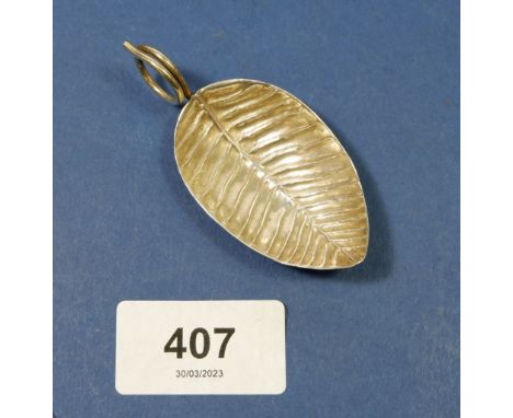 A silver caddy spoon in the shape of a leaf 
