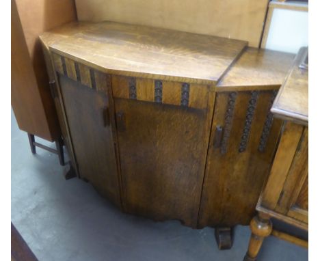 A TWENTIETH CENTURY OAK BREAKFRONT SIDEBOARD, THE CENTRE CUPBOARD ENCLOSING TWO SLIDES OVER SHELF WITH CUPBOARD TO EACH SIDE 