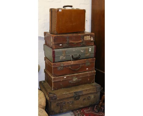 A leather bound travel trunk along with five assorted suitcases.