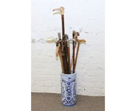 A modern Chinese blue and white stick stand and a large collection of walking sticks and walking canes including silver mount