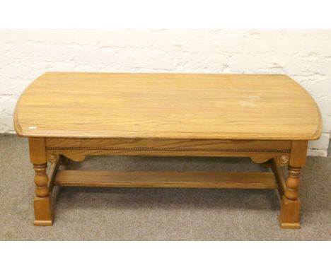 A carved light oak coffee table raised on turned and square cut legs.