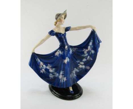 A Goldscheider pottery early 20thC figure of a dancer, modelled by Stephen Dakon, in a floral blue dress and hat, an oval bas