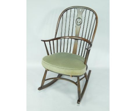 An Ercol oak spindle back rocking chair, with loose green draylon cushion.