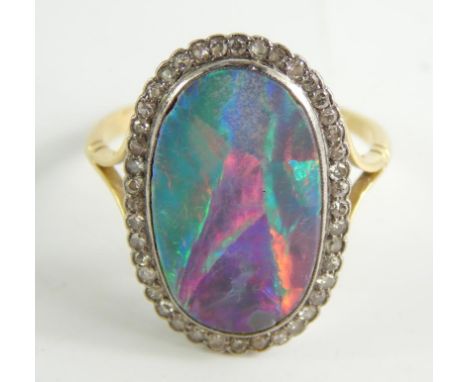 An opal and diamond ring, the central oval opal approx 20mm x 12mm x 4mm, surrounded by diamonds, yellow metal, marked 18ct, 