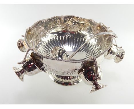A plated semi fluted punch bowl, with twin lion's head and ring handles, embossed with flowers together with six cups and a K