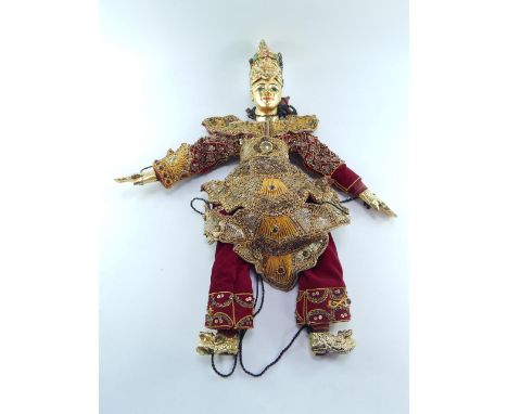 A Thai puppet with jointed head and limbs, painted and gilded, with an ornate beaded and jewelled costume, 52cm high.
