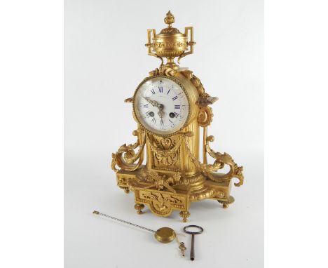 A French late 19thC ormolu mantel clock, the barrel case with urn surmount, enamel dial bearing Arabic and Roman numerals, ei